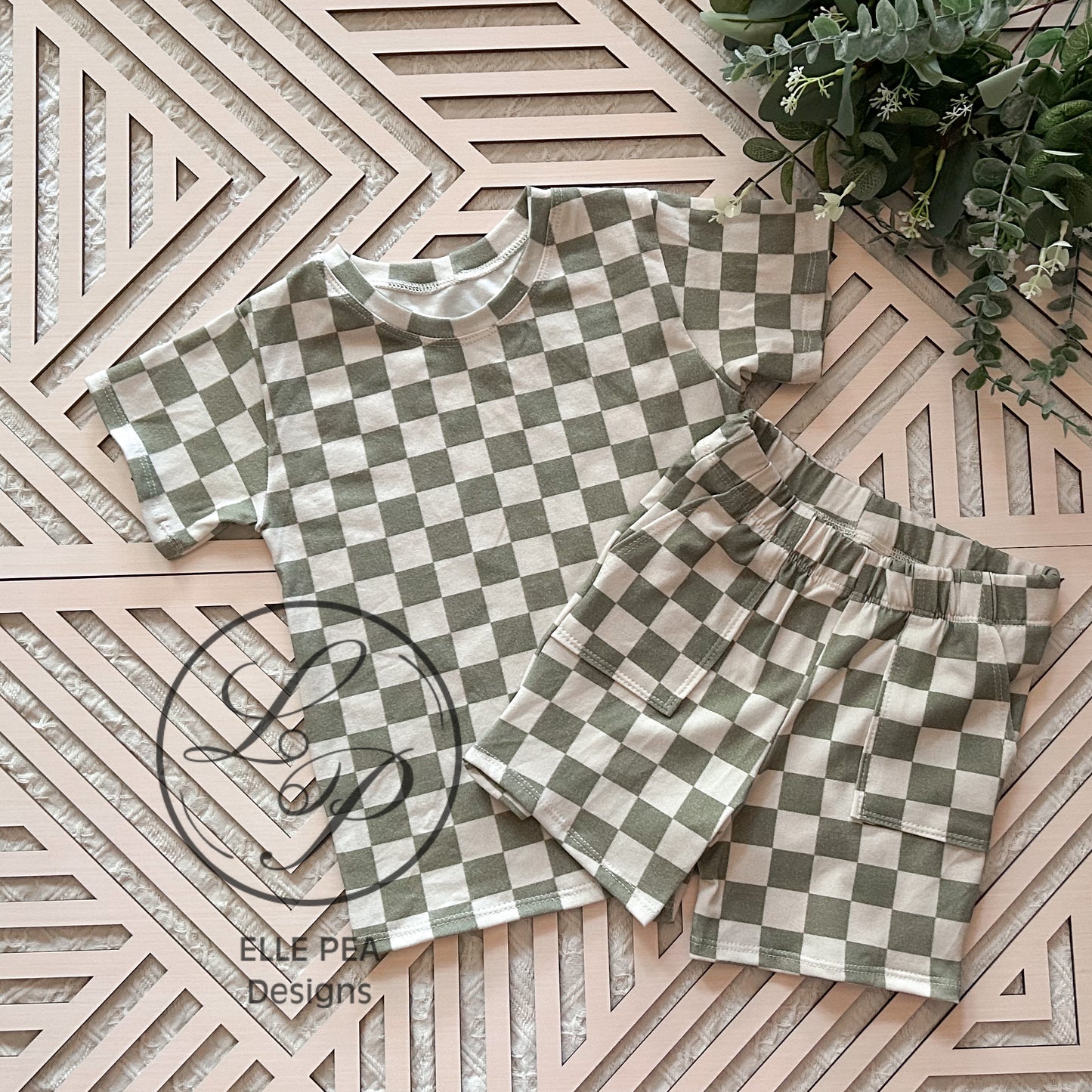 Checkered shirt and shorts set on a geometric patterned surface with 'ELLE PEA Designs' logo.
